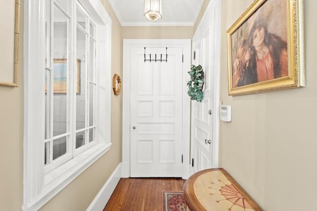 doorway to outside with dark wood-style flooring, ornamental molding, and baseboards