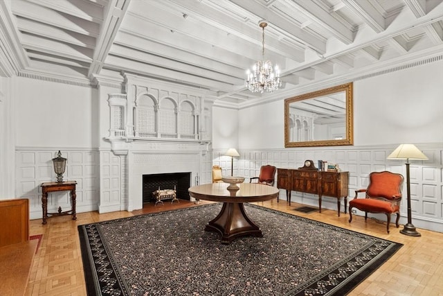 living area with a chandelier, a fireplace with flush hearth, beamed ceiling, crown molding, and wainscoting