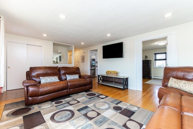 living room featuring a baseboard heating unit and light hardwood / wood-style flooring