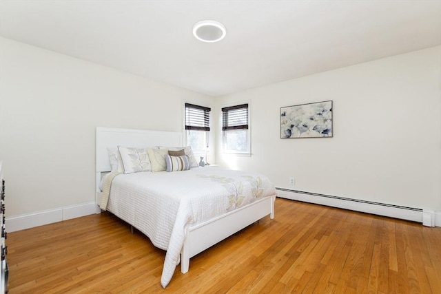 bedroom featuring a baseboard heating unit and light hardwood / wood-style floors