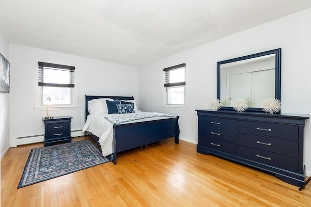 bedroom featuring baseboard heating and light hardwood / wood-style flooring