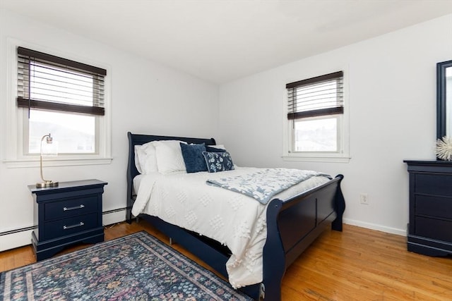 bedroom with light hardwood / wood-style flooring and baseboard heating