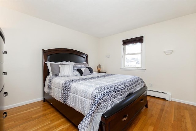 bedroom with light hardwood / wood-style flooring and baseboard heating