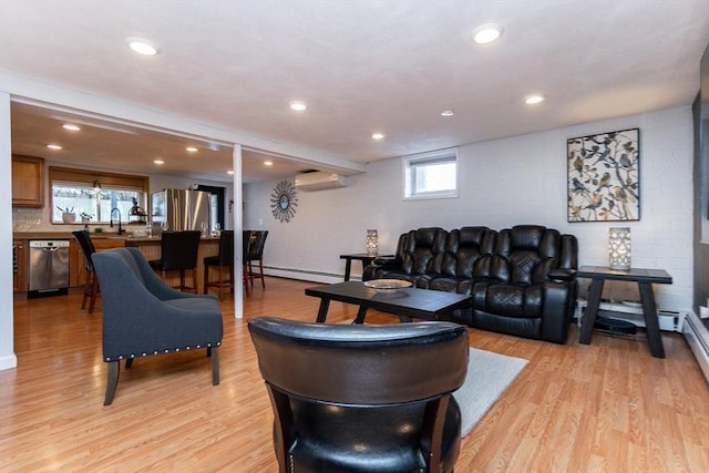 living room featuring sink, a baseboard heating unit, a wall mounted air conditioner, and light hardwood / wood-style floors