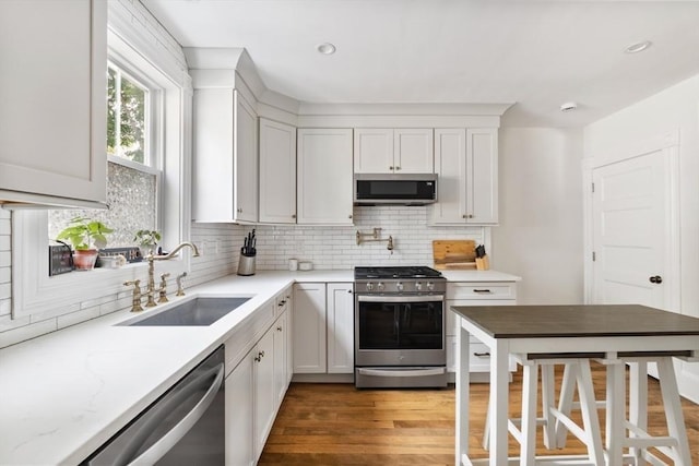 61 Elm St Unit 61, Andover, MA 01810 - kitchen featuring appliances with stainless steel finishes, decorative backsplash, wood finished floors, white cabinetry, and recessed lighting