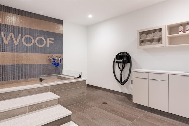 bathroom featuring recessed lighting, tiled shower, baseboards, and wood finished floors