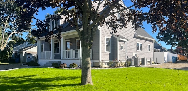 view of front of house with a front yard, a porch, and central AC unit