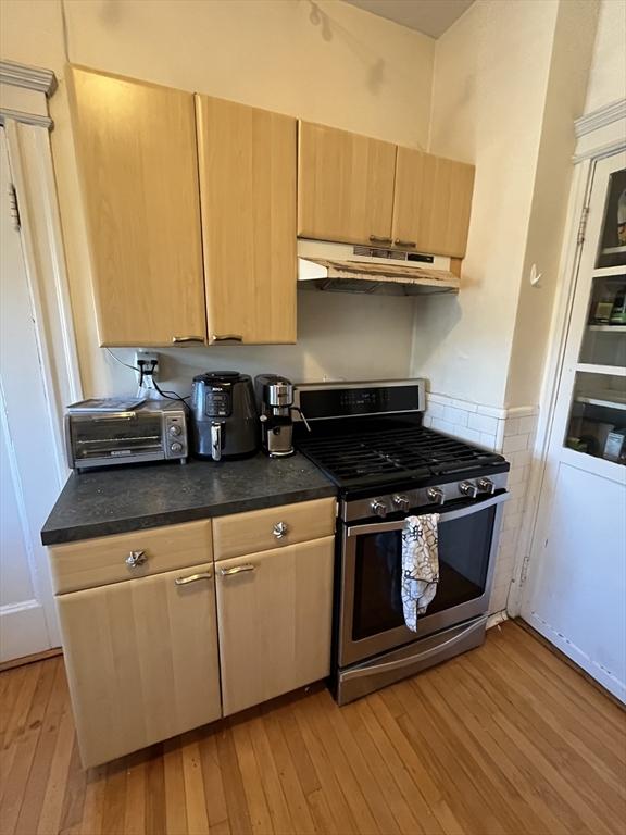 kitchen with stainless steel gas range, light brown cabinetry, and light hardwood / wood-style flooring