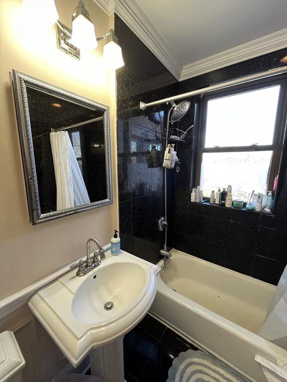 bathroom with crown molding and shower / bath combination with curtain