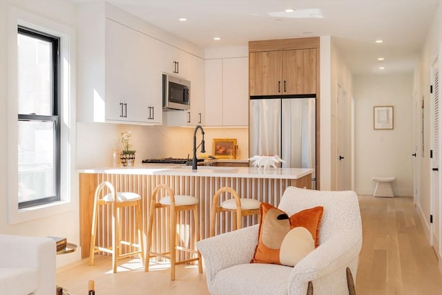 kitchen featuring a peninsula, a kitchen breakfast bar, light countertops, and stainless steel appliances