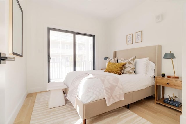 bedroom featuring light wood-style flooring, baseboards, and access to outside