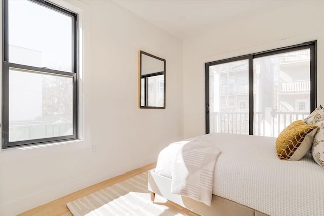 bedroom featuring access to outside, wood finished floors, and baseboards