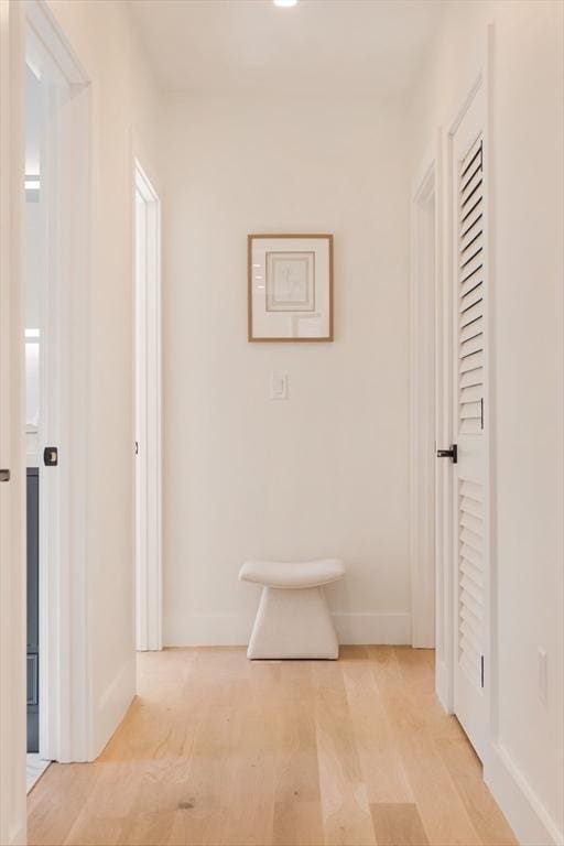 corridor featuring light wood finished floors and baseboards