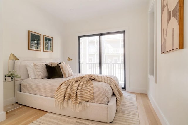 bedroom featuring access to exterior, baseboards, and light wood-style floors