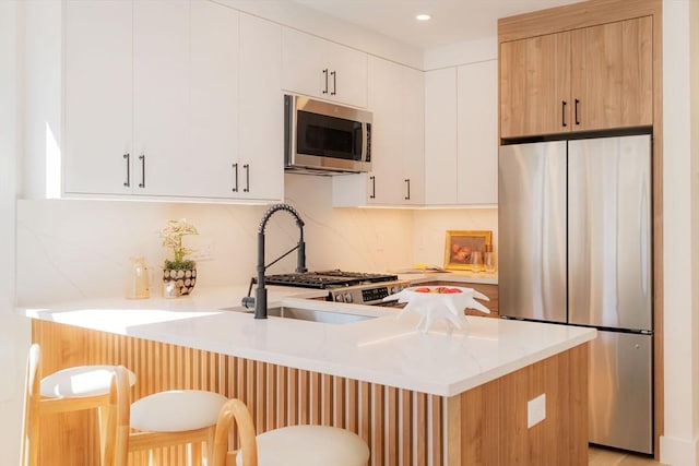 kitchen with a peninsula, a breakfast bar area, tasteful backsplash, and stainless steel appliances