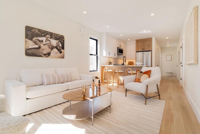 living area with recessed lighting, baseboards, and light wood-style flooring