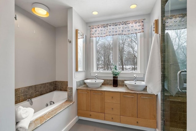 full bath featuring double vanity, a tub with jets, a stall shower, and a sink