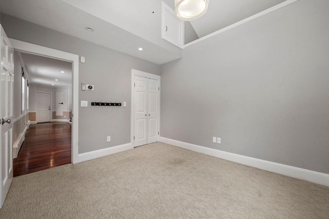 carpeted empty room featuring high vaulted ceiling, recessed lighting, and baseboards