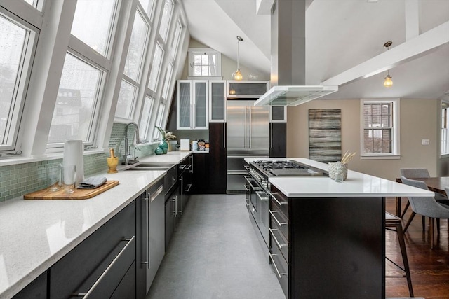 kitchen with premium appliances, dark cabinets, light countertops, a center island, and glass insert cabinets