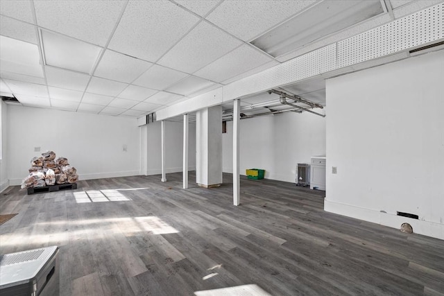 basement with a paneled ceiling and dark hardwood / wood-style flooring