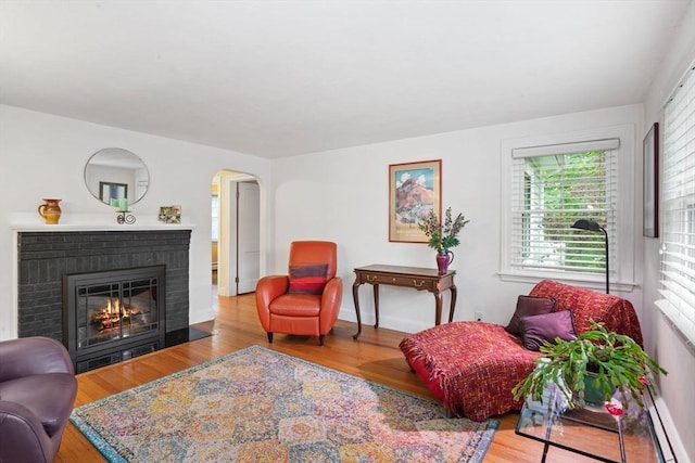 304 Hunting Rd, Needham, MA 02494 - living area featuring wood finished floors, a brick fireplace, a baseboard heating unit, and arched walkways