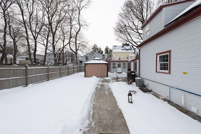 yard layered in snow featuring central AC and an outbuilding