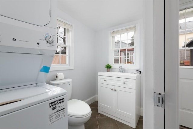 bathroom with vanity, plenty of natural light, stacked washer and clothes dryer, and toilet