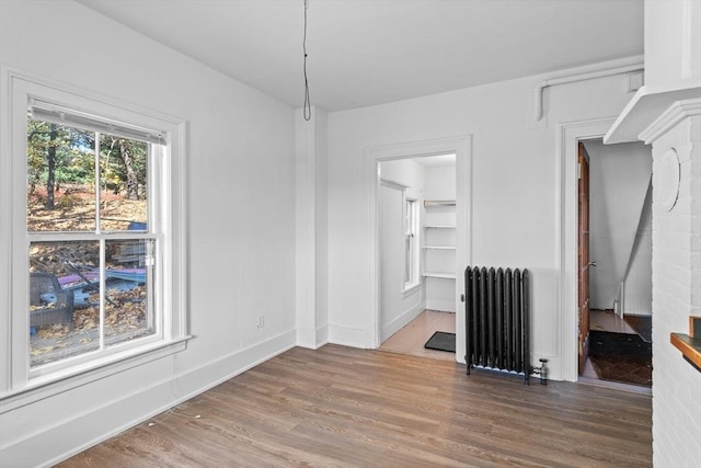 unfurnished dining area featuring hardwood / wood-style flooring and radiator heating unit