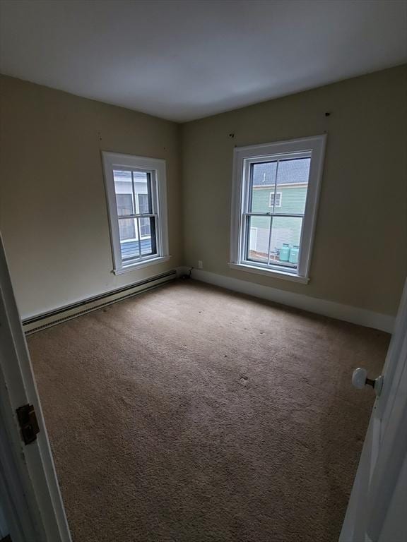 spare room with carpet flooring and a baseboard heating unit