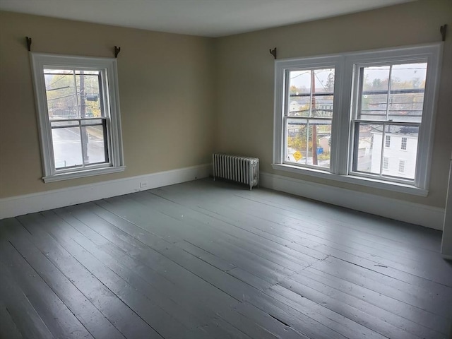 unfurnished room featuring hardwood / wood-style floors and radiator heating unit