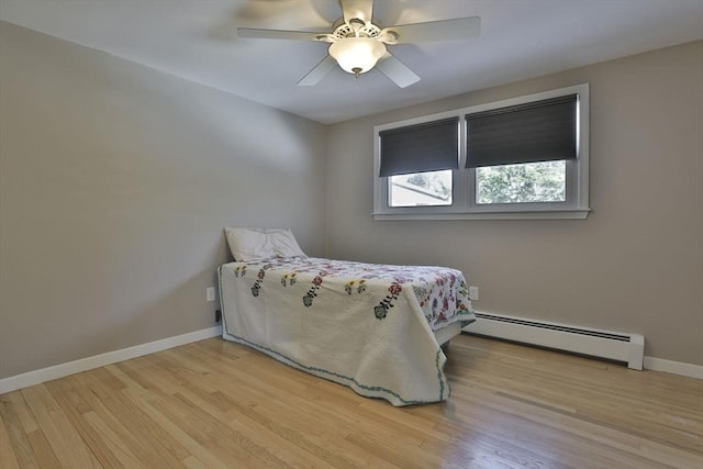 bedroom with a baseboard heating unit, wood finished floors, baseboards, and a ceiling fan