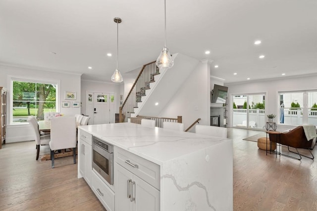 94 Webster Unit 94, Newton, MA 02465 - kitchen with crown molding, stainless steel microwave, light wood-style floors, recessed lighting, and light stone counters