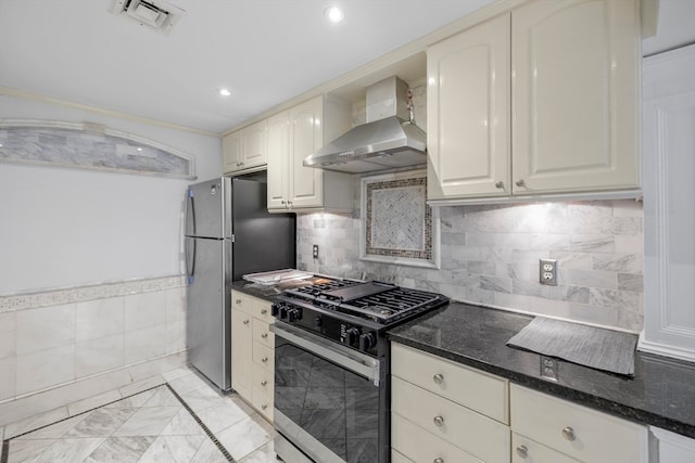 kitchen featuring stainless steel appliances, tasteful backsplash, dark stone counters, and wall chimney range hood