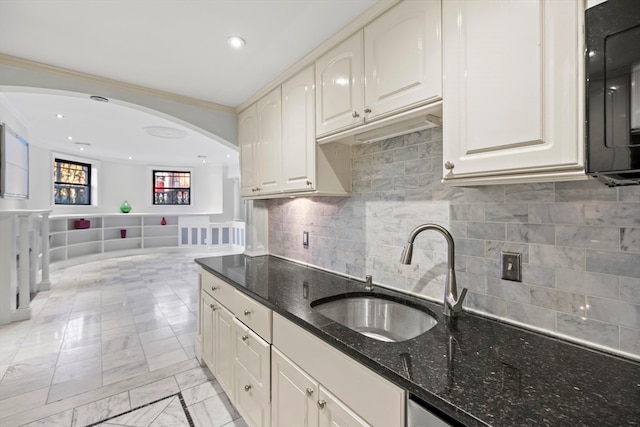 kitchen with decorative backsplash, ornamental molding, dark stone counters, and sink