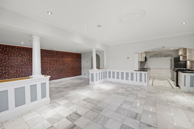 unfurnished living room with ornamental molding, sink, and brick wall