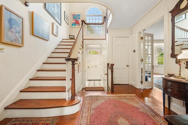 foyer entrance featuring wood finished floors, stairway, and baseboards