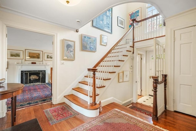 stairs with wood finished floors, a fireplace, and baseboards
