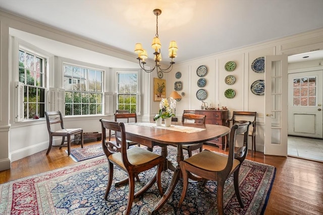 dining area with a chandelier, plenty of natural light, ornamental molding, light wood-type flooring, and baseboards