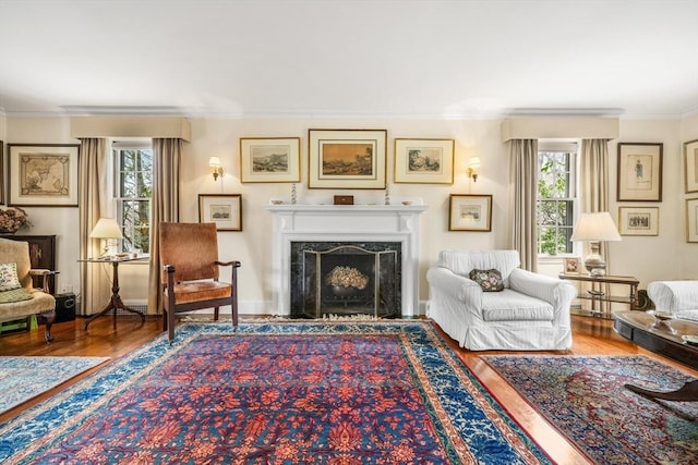 living area with crown molding, plenty of natural light, wood finished floors, and a fireplace