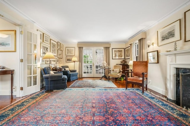 living area featuring french doors, wood finished floors, ornamental molding, a fireplace, and baseboards
