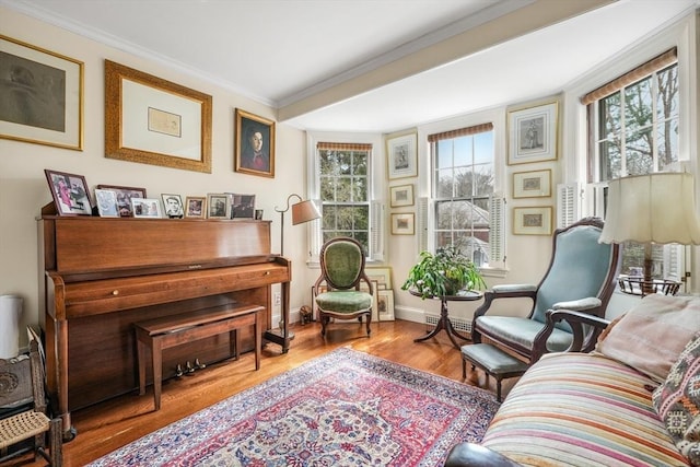 sitting room with plenty of natural light, wood finished floors, ornamental molding, and baseboards