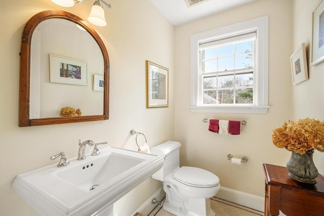 bathroom featuring a sink, toilet, and baseboards