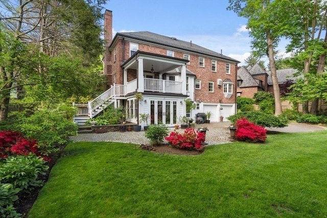 back of property featuring a chimney, a yard, a garage, stairway, and french doors