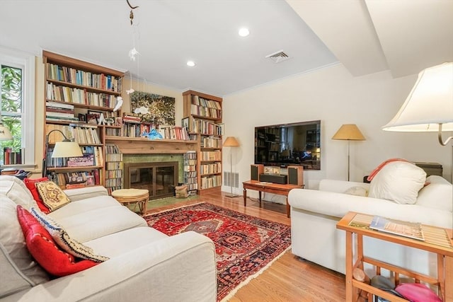 living area featuring wood finished floors, recessed lighting, and a glass covered fireplace