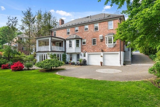 rear view of property featuring asphalt driveway, a chimney, a yard, stairway, and a garage