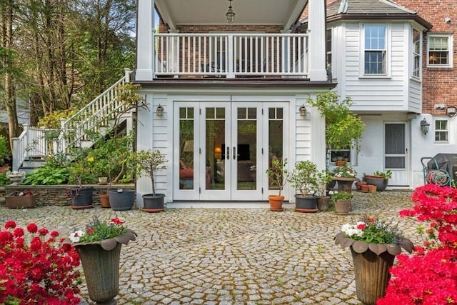 back of house featuring french doors, a balcony, and stairs
