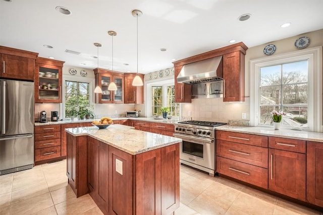 kitchen with stainless steel appliances, wall chimney exhaust hood, healthy amount of natural light, and recessed lighting