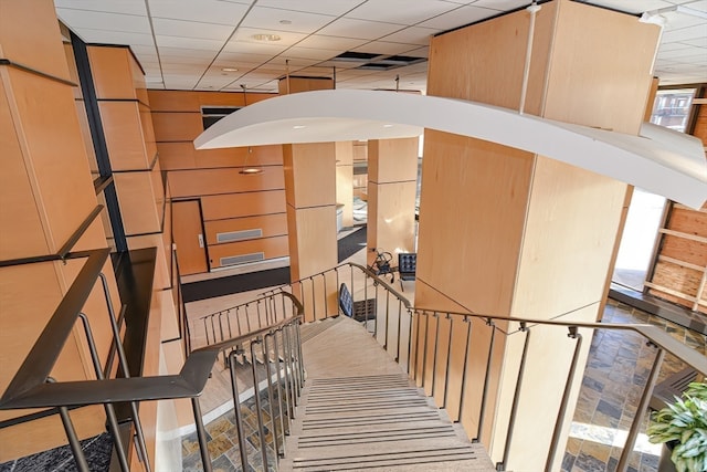 stairway featuring a paneled ceiling and carpet