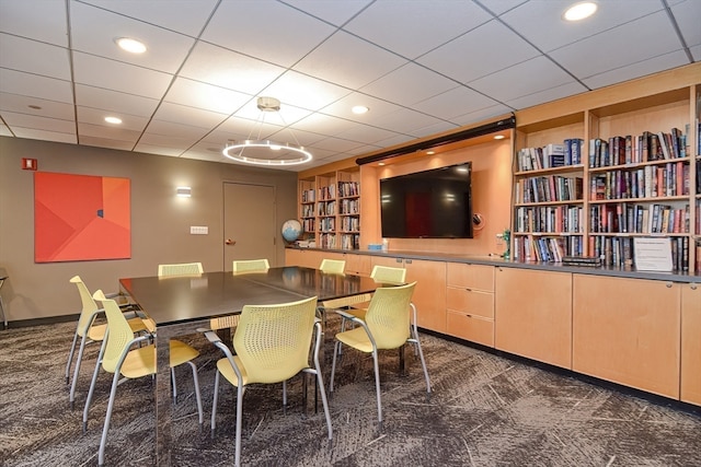 carpeted dining space with a notable chandelier and a paneled ceiling