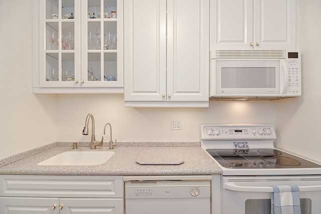 kitchen with white appliances, white cabinetry, and sink